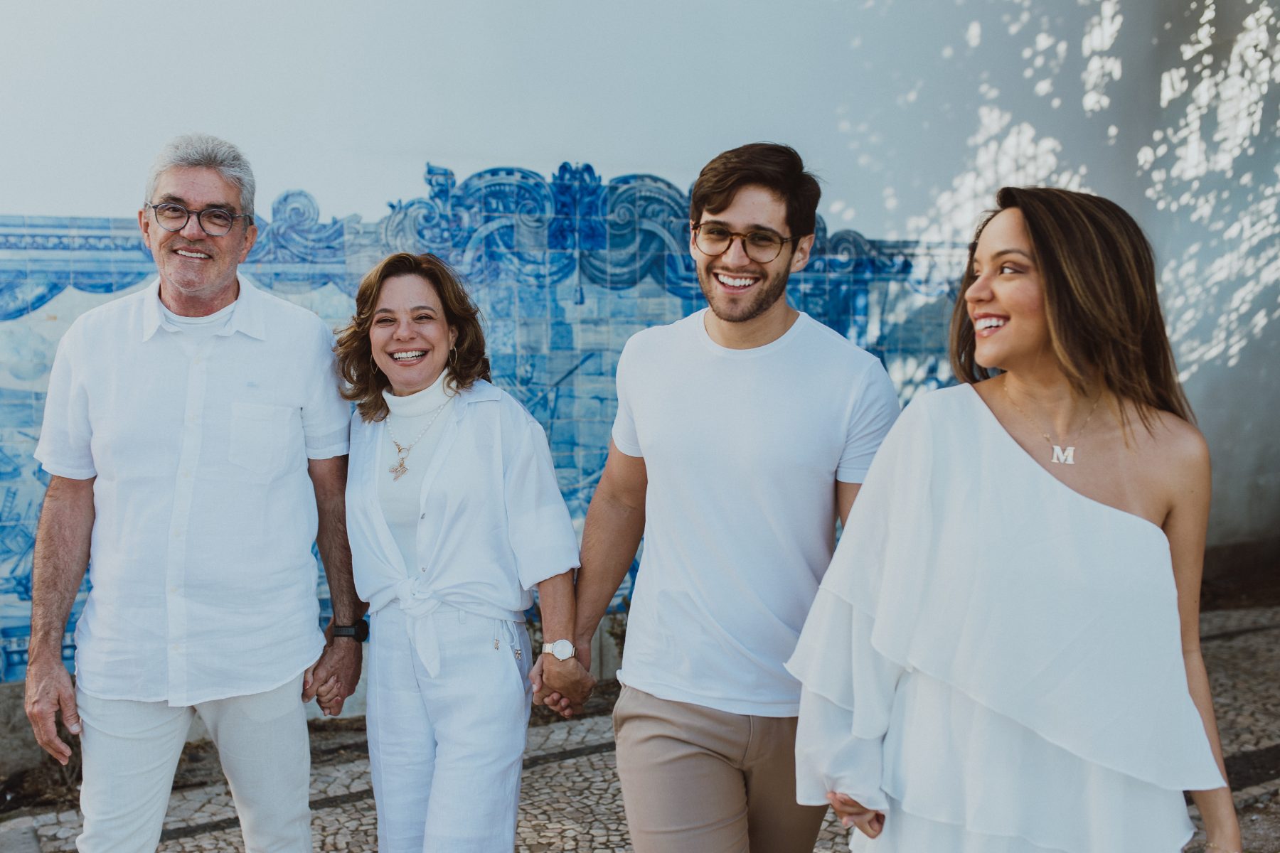 Família rindo diante de um painel de azulejos azuis
