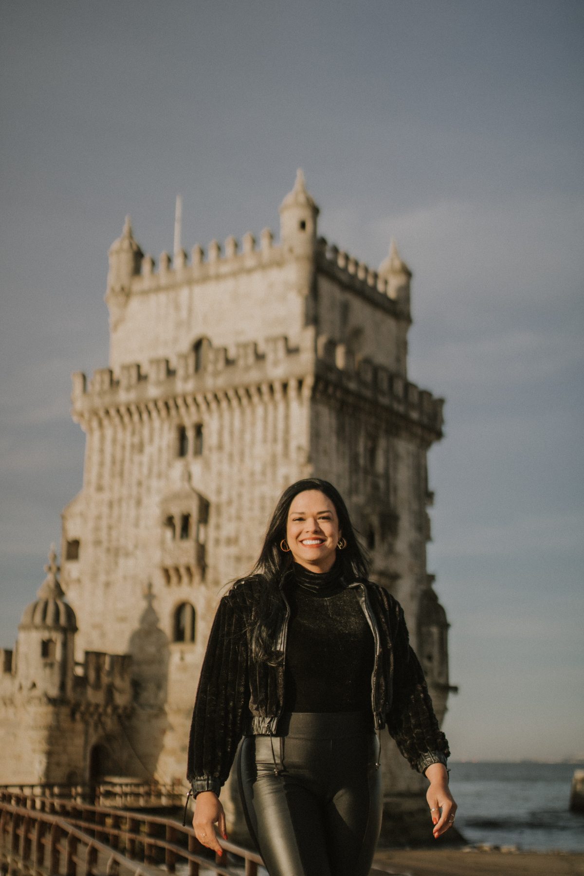 Mulher sorrindo diante da Torre de Belém